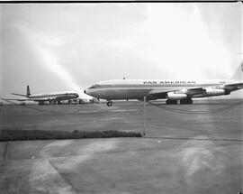 Pan American Airlines (PAA) Boeing 707 jet passes a de Havilland Comet 4 jet on runway